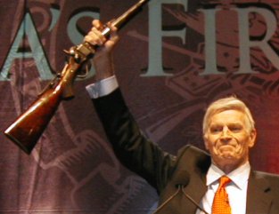 Charlton Heston brandit un fusil pendant une réunion de la  National Rifle Association