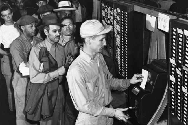Ford Motor Company workers punching their time cards at the time clock.