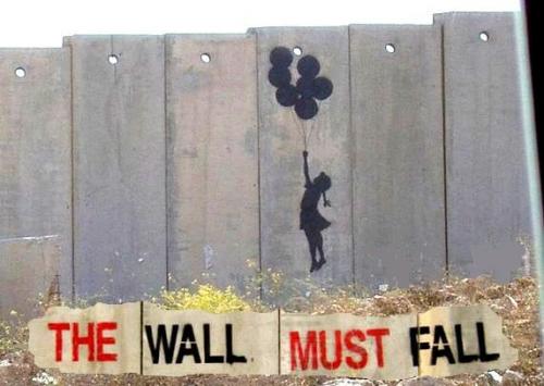 “The Wall must fall”, opera ‎dell’artista inglese Bansky realizzata sul muro di separazione eretto dal governo israeliano in ‎Cisgiordania.‎<br />
