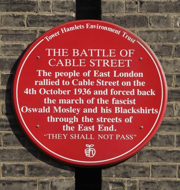 A plaque commemorating the Battle of Cable Street is mounted on a wall in London, England