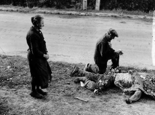 Due francesi depongono fiori sul corpo di un soldato americano ucciso