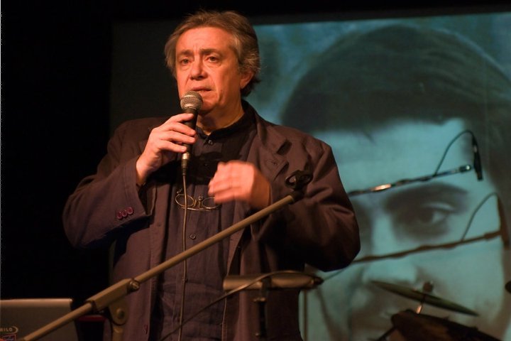 Emilio Insolvibile adesso, con sullo sfondo la copertina del suo vecchio album Amore guerra e societ&agrave;.