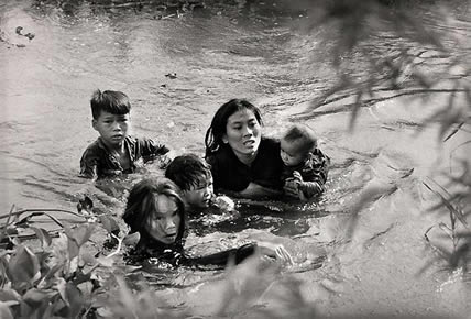 1965. A mom and her ‎children try to cross the river in South Vietnam in an attempt to run away from the American ‎bombs, photo by Kyoichi Sawada