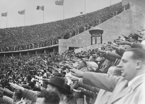 Dans le Stade Olympique, les spectateurs allemands saluent Adolf Hitler lors des 11èmes Jeux Olympiques. Berlin, Allemagne, août 1936.