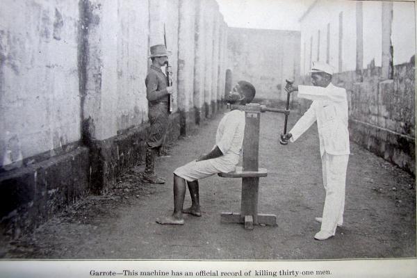 Circa 1900. Esecuzione con garrota spagnola di un ribelle filippino, A sinistra, un soldato statunitense piantona il condannato.