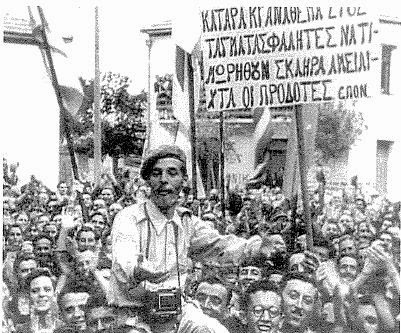 La popolazione di un paese greco accoglie festante i "Liberatori" inglesi nel 1945. Nel cartello si richiede l' "esemplare e dura punizione dei traditori Tagmatasfalites", che gli inglesi stavano già mettendo al loro servizio.